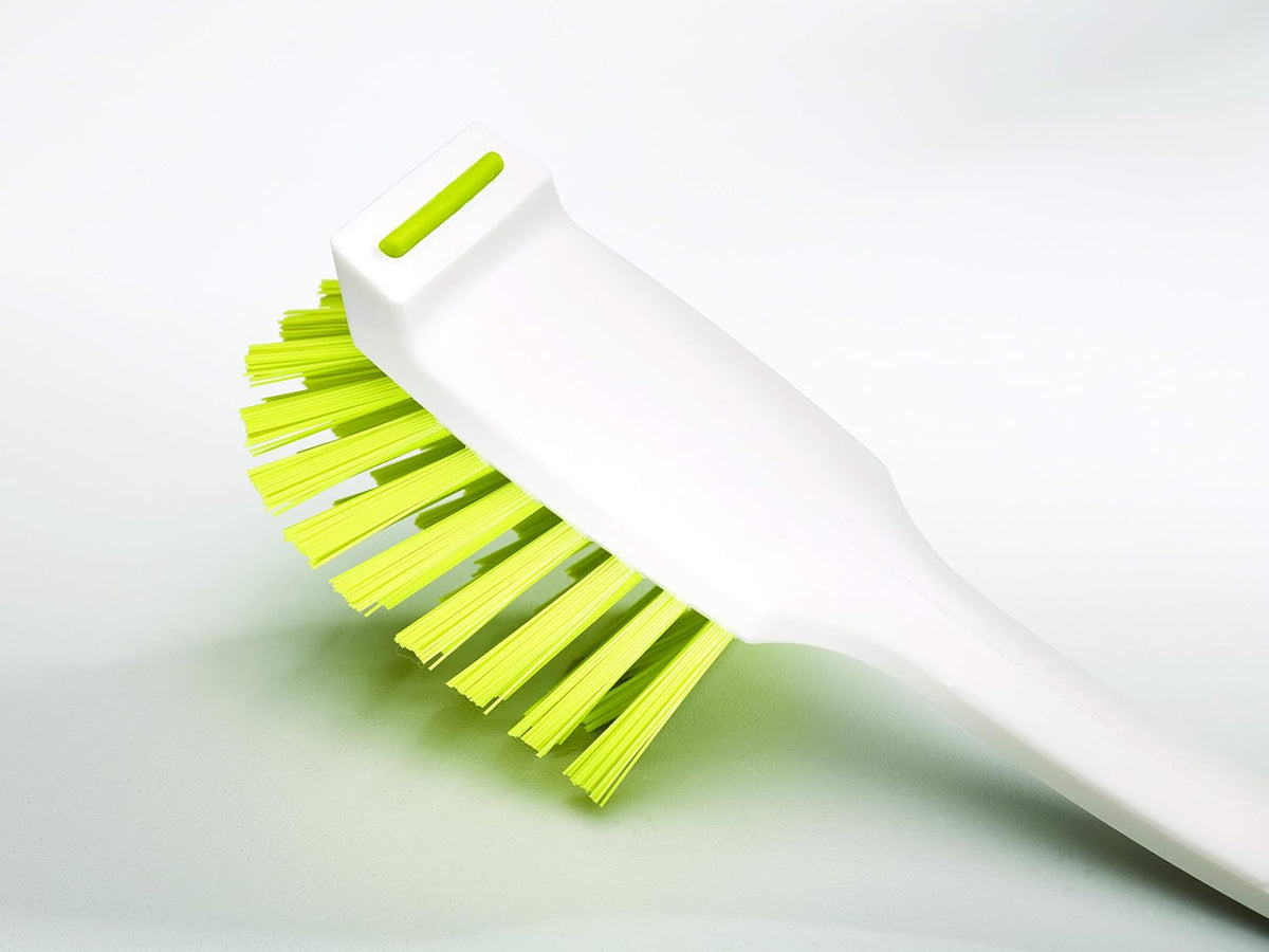 curved brush head designed to reach corners of trays and pans